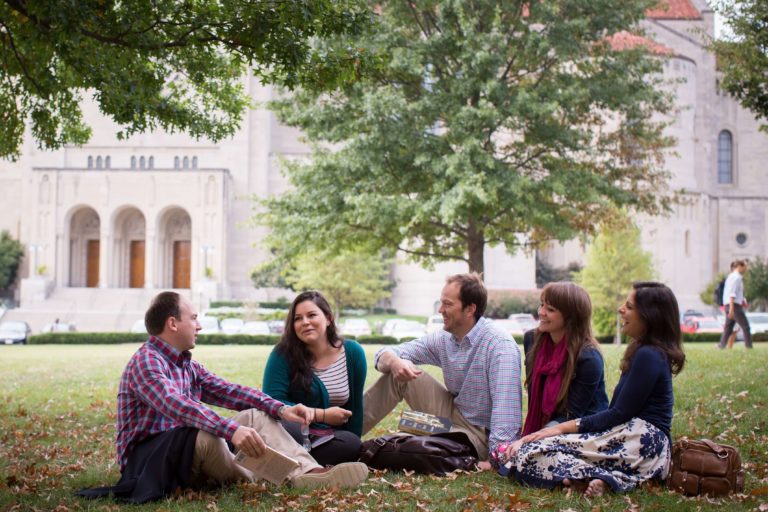 JPII Institute theology masters students sitting on the lawn laughing