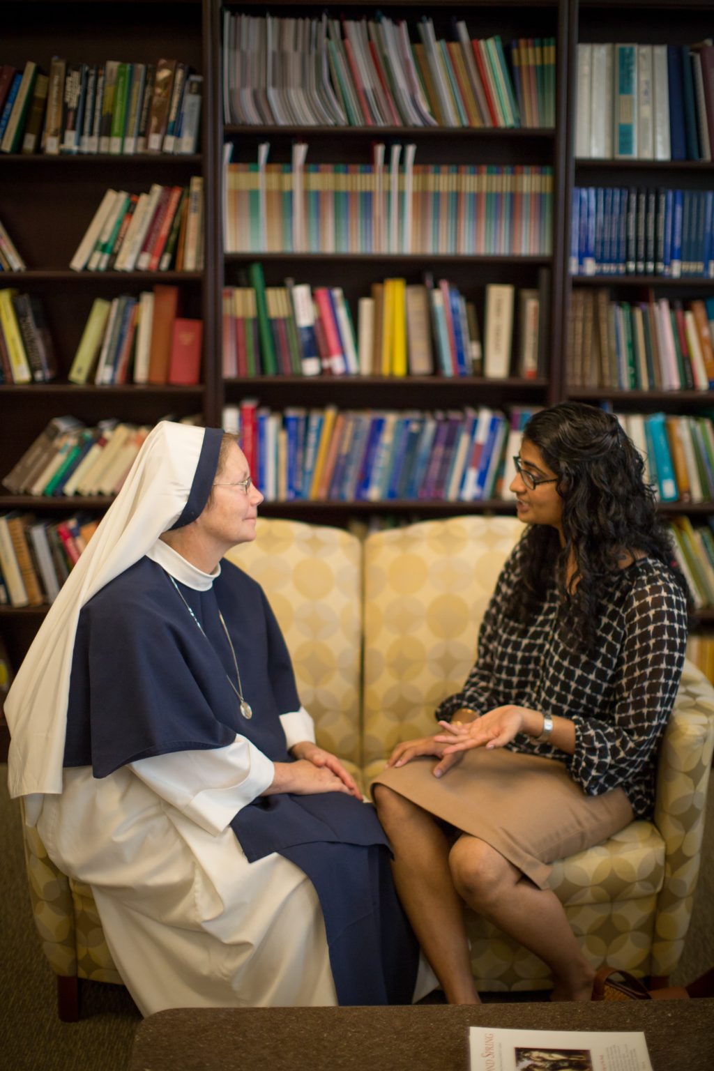 A nun and a female student having a conversation in a library