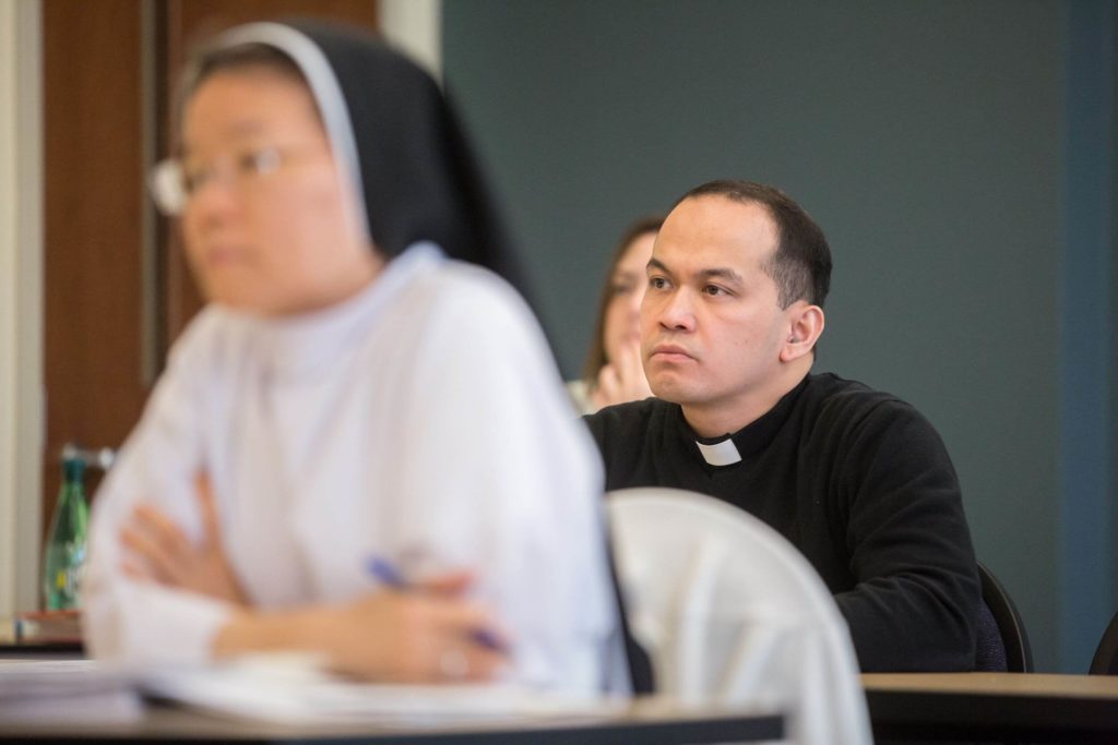 Religious sister and priest listening in classroom