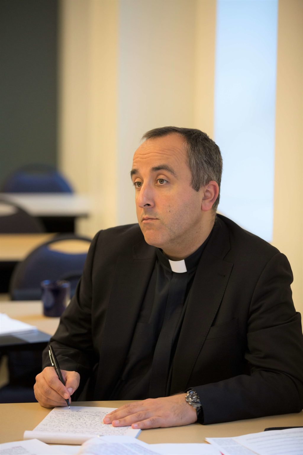 Priest listening during theology lecture in classroom