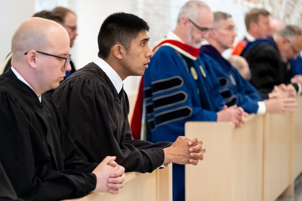 Theology graduates and faculty praying during graduation liturgy