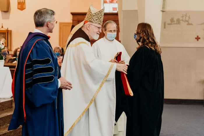 John Paul II Graduation 2021 prief delivering diploma to student