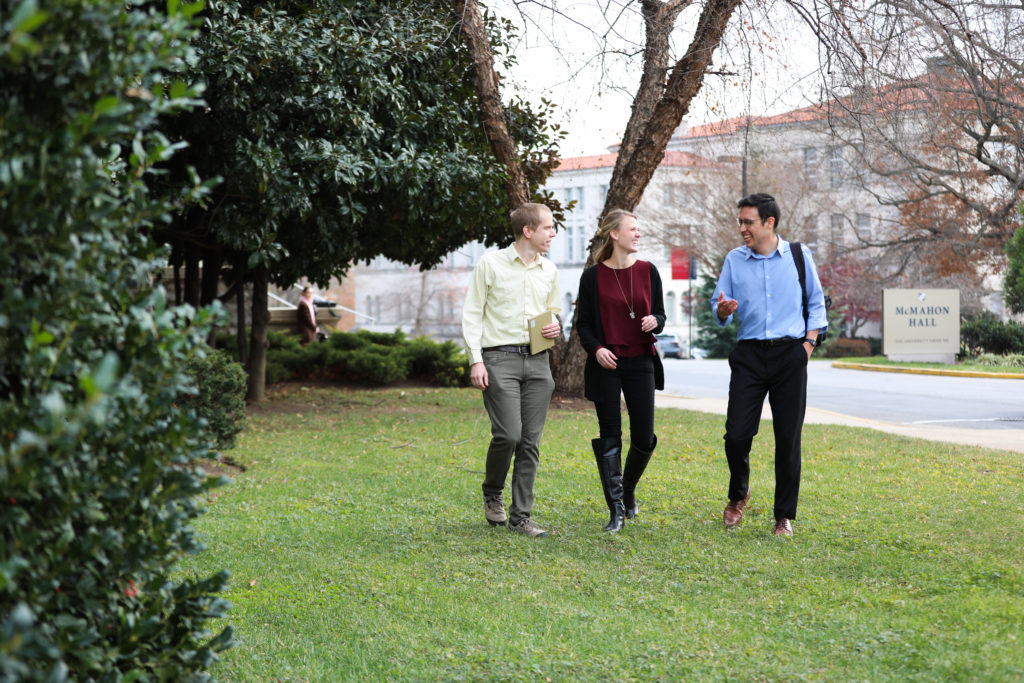 Three students talking and walking on grass
