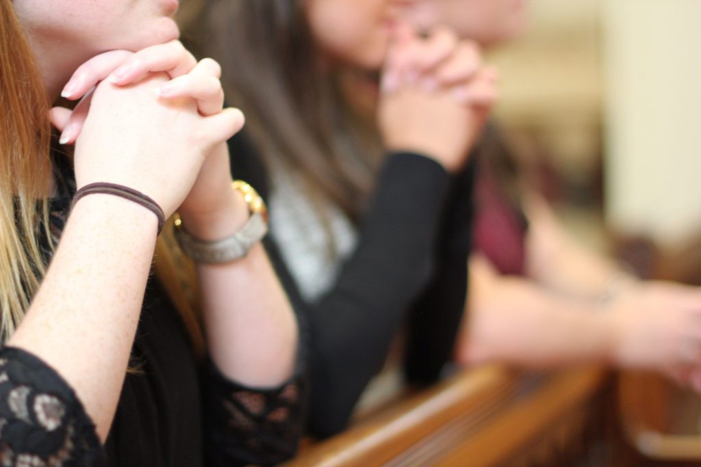 People kneeling and praying with their hands at church